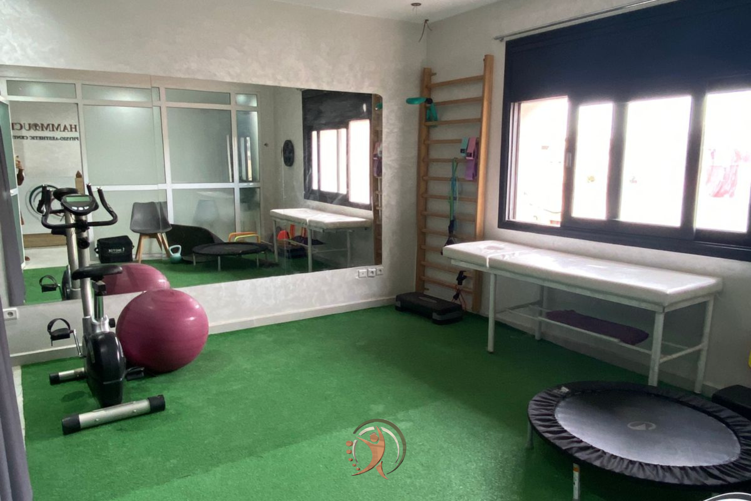 Salle de rééducation fonctionnelle du Hammouch Physio-Aesthetic Center à Fès, équipée d’un vélo d’exercice, de ballons de rééducation, d’un espalier mural et d’une table de kinésithérapie. L’espace lumineux et moderne est conçu pour accompagner les patients dans leur récupération, renforcer la mobilité et favoriser le bien-être physique.